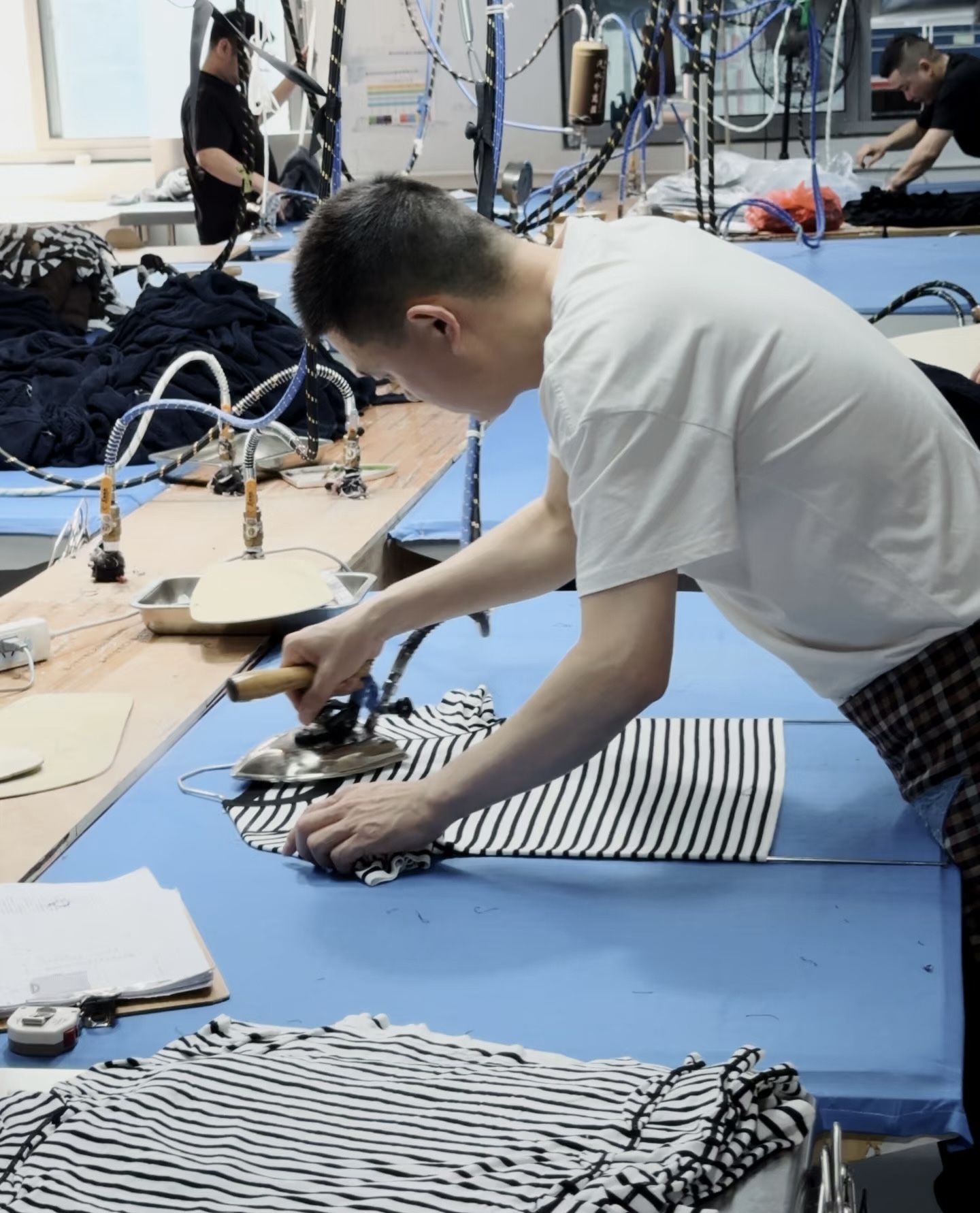 Ironing & Pressing — operator steam-pressing finished knitwear on industrial ironing station